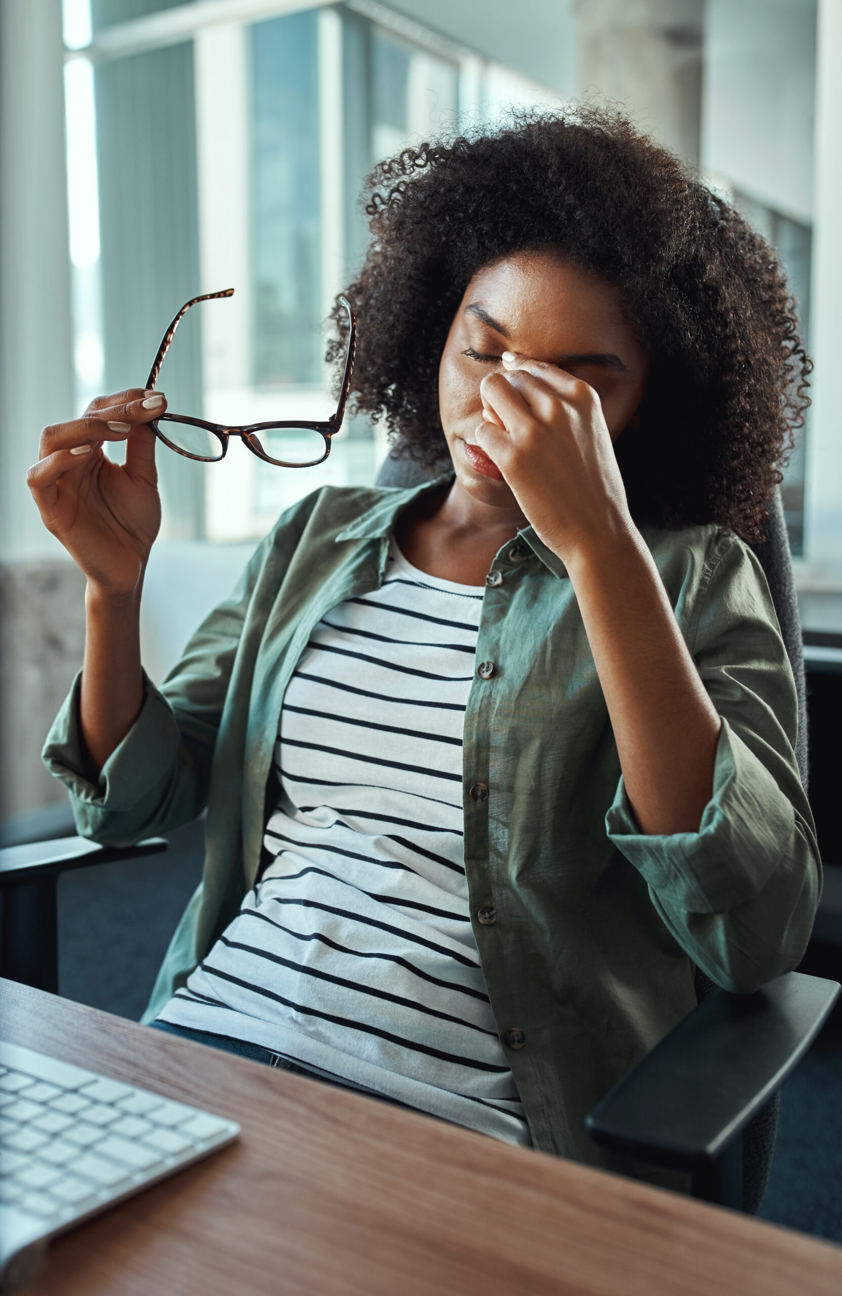 stressed young african woman holding eyeglasses relaxing for while sitting at office desk