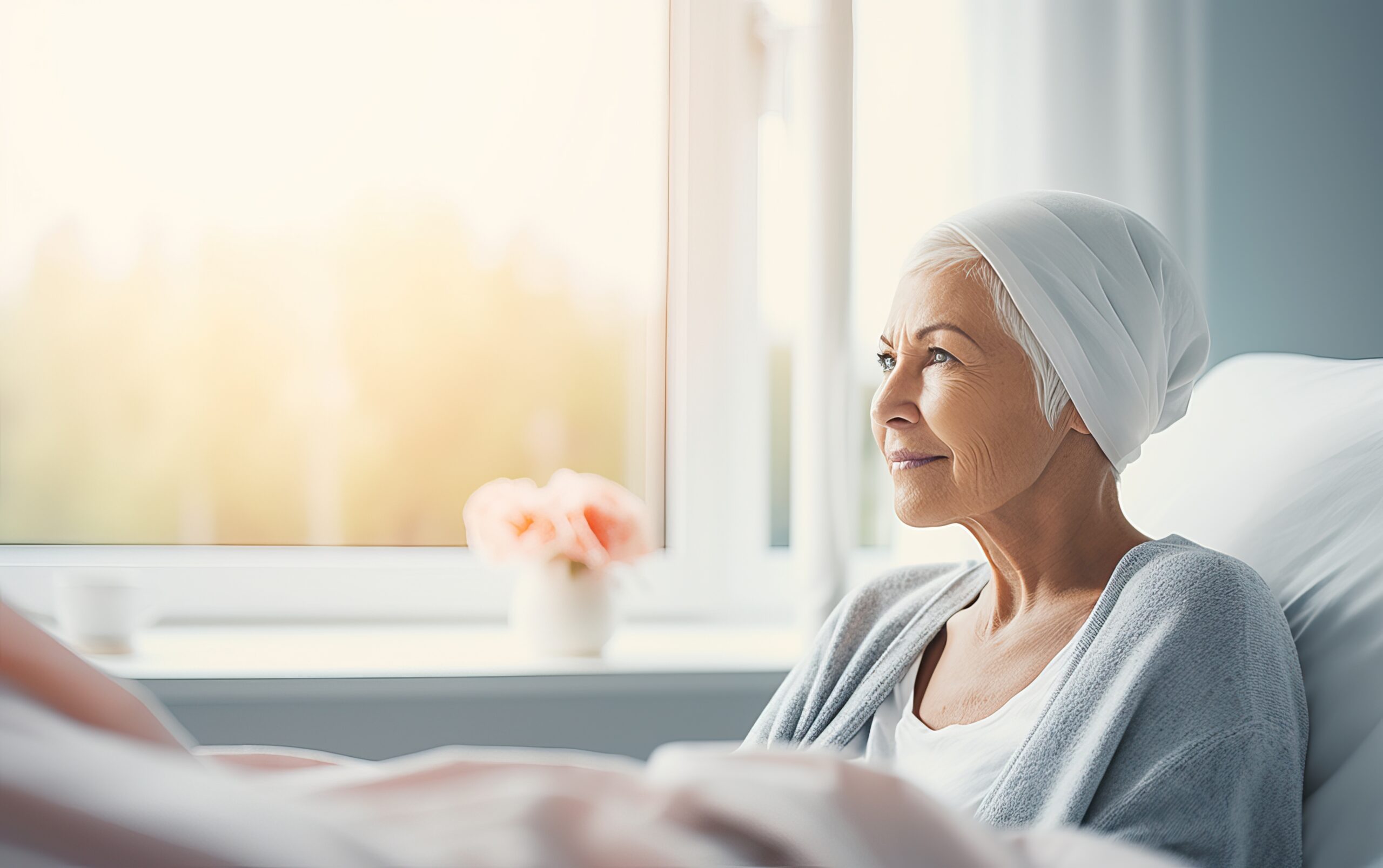 Senior sad woman wearing headscarf, suffering from bone cancer sitting alone at a hospital